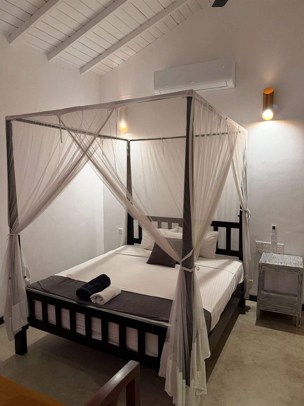 A four-poster canopy bed draped with mosquito nets in the triple budget room